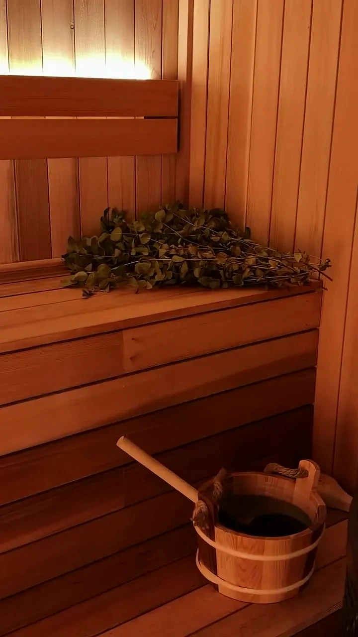 Sauna bench with an oak venik and a wooden bucket